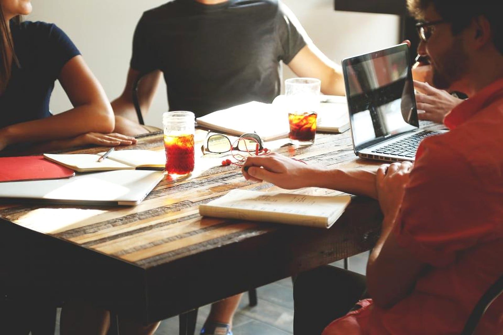 Pessoas reunidas em uma mesa de trabalho com notebook e anotações