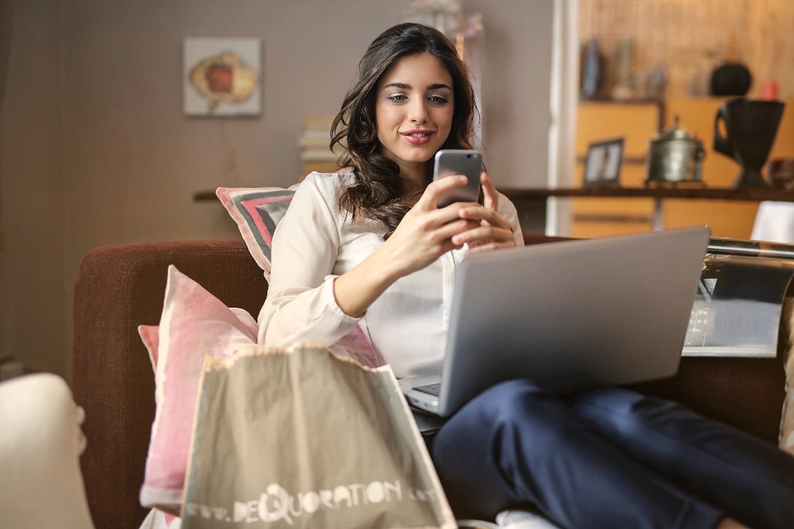Mulher ao telefone, sorrindo, com o notebook à frente