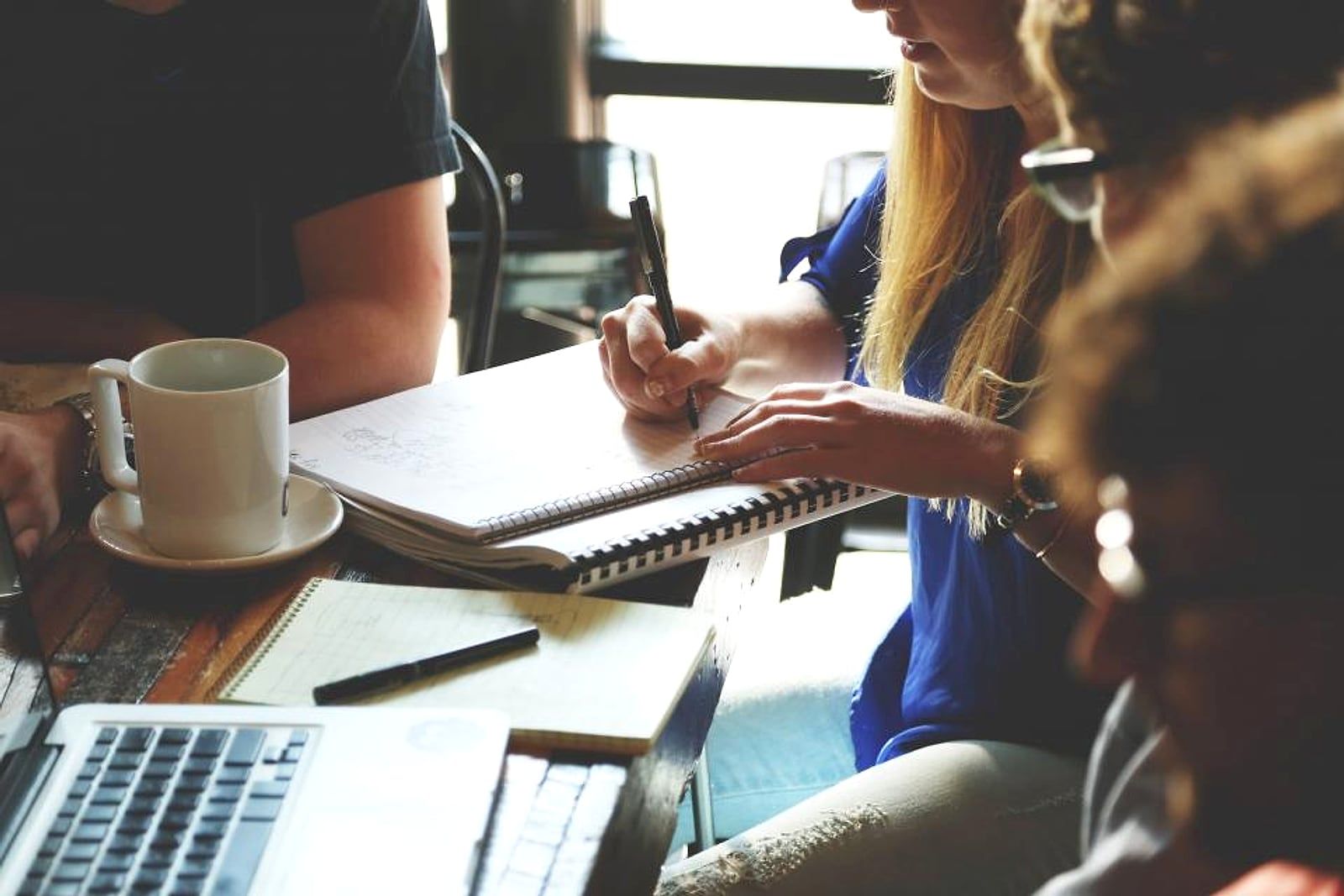 Equipe trabalhando em conjunto em uma mesa, com notebook e anotações